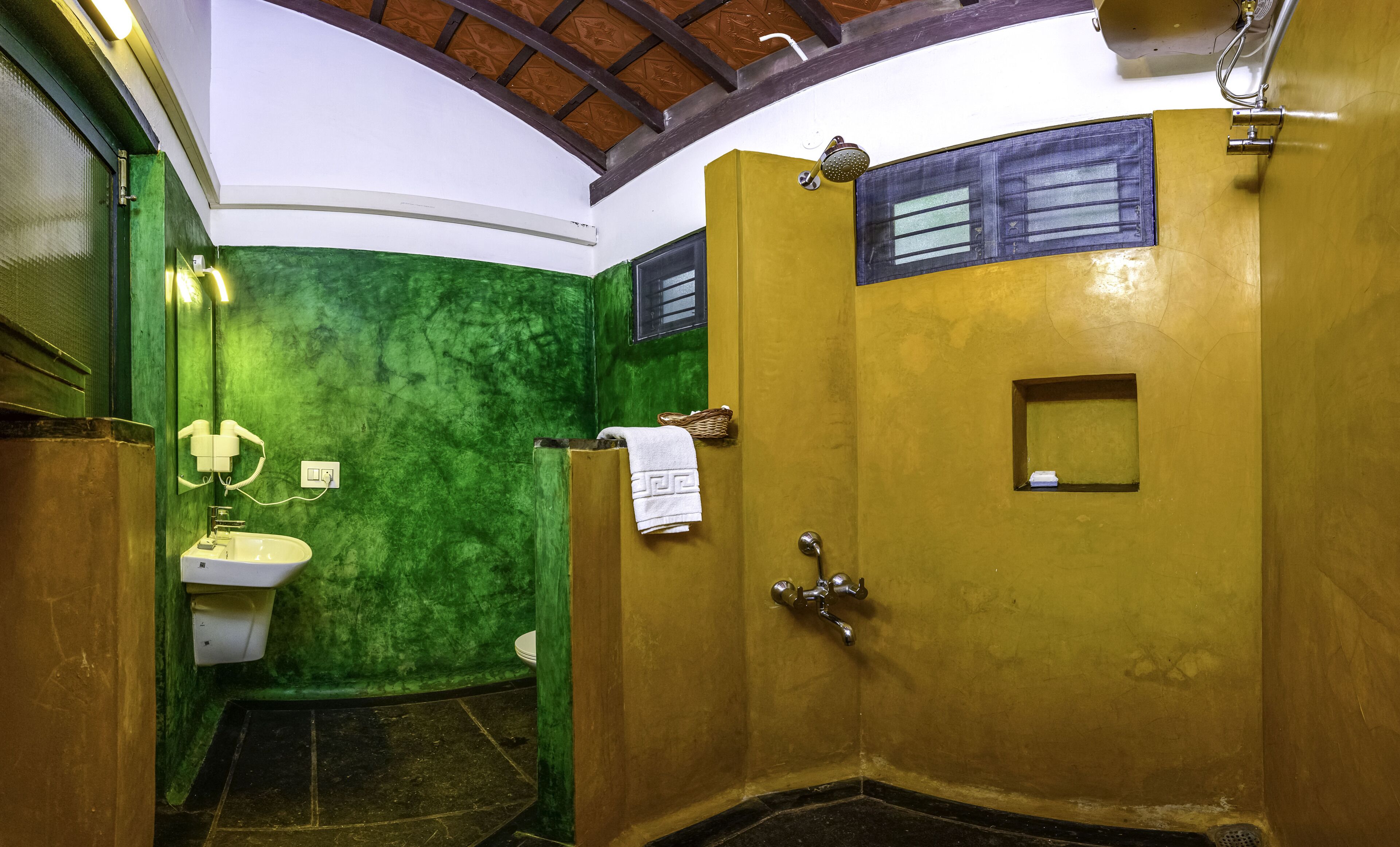 A bathroom with a green wall, a white sink, and a shower area.