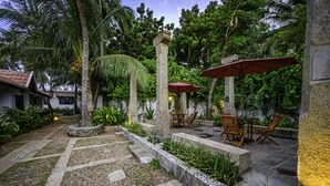 Un patio con senderos de piedra, palmeras y mobiliario exterior.