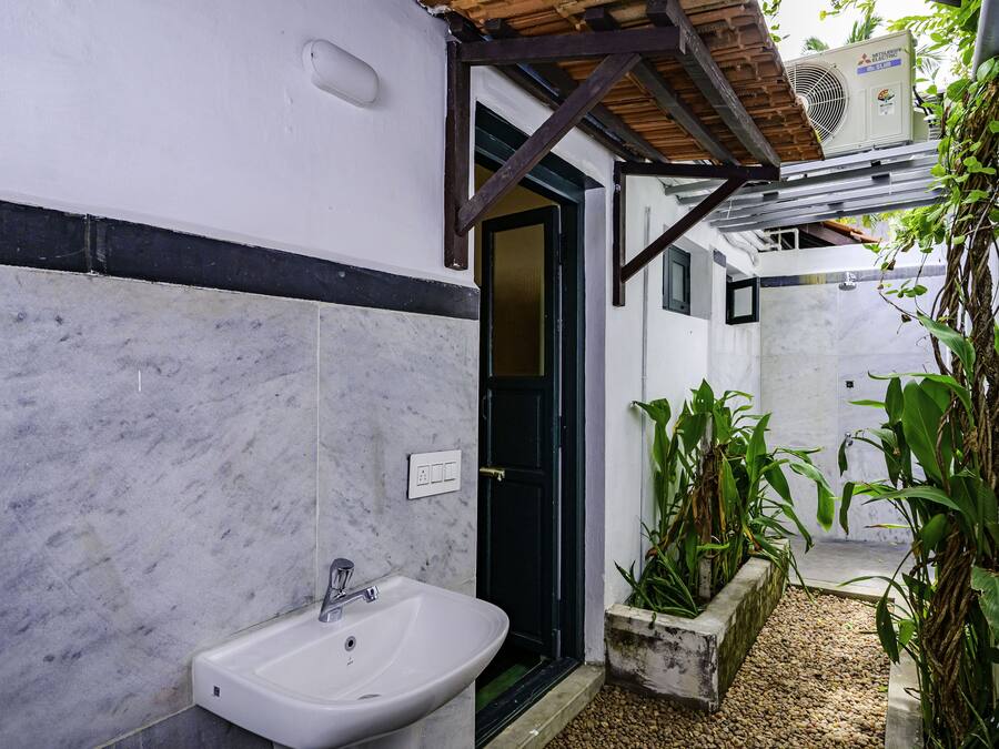 A bathroom with a sink, a door, and a small garden area with plants.