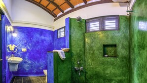 Un baño con un esquema de color azul y verde distintivo, un lavamanos, una ducha y una ventana.