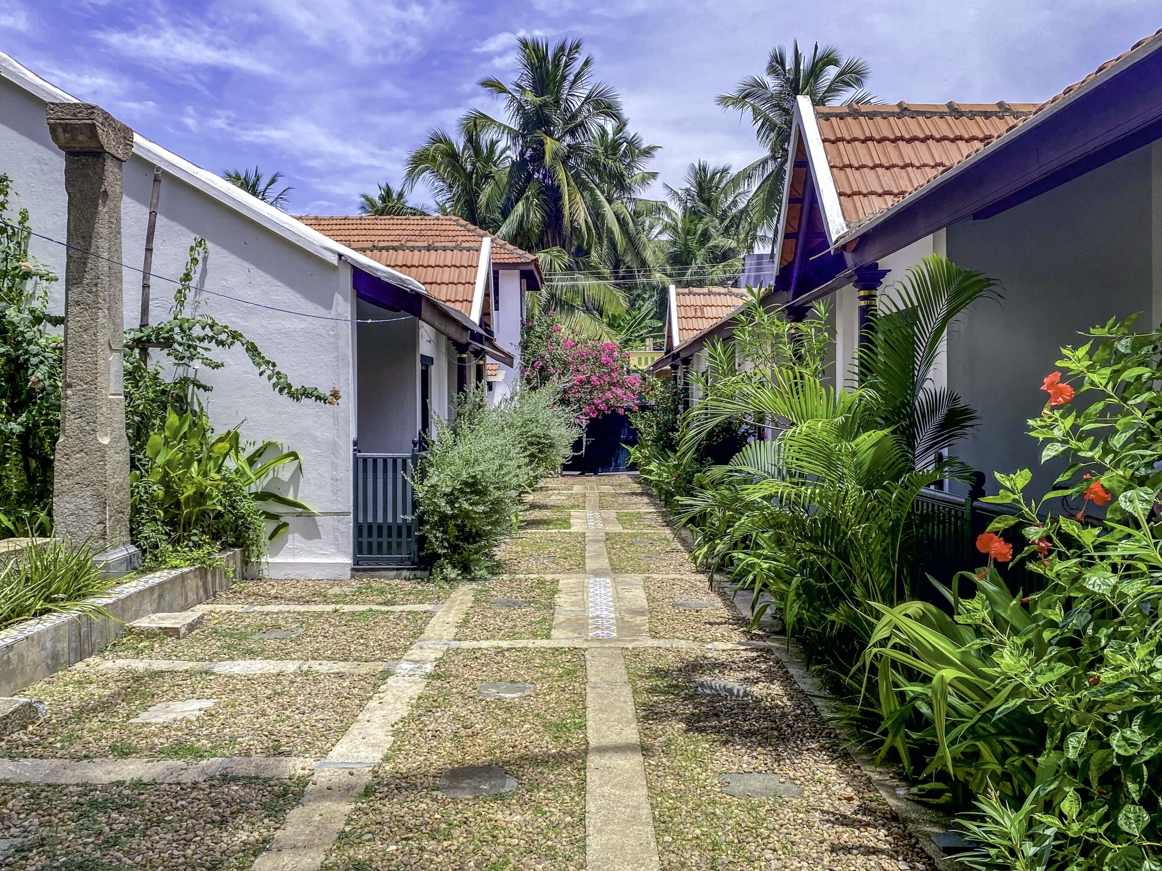 A narrow pathway flanked by buildings with tiled roofs, leading to a central area with a staircase.