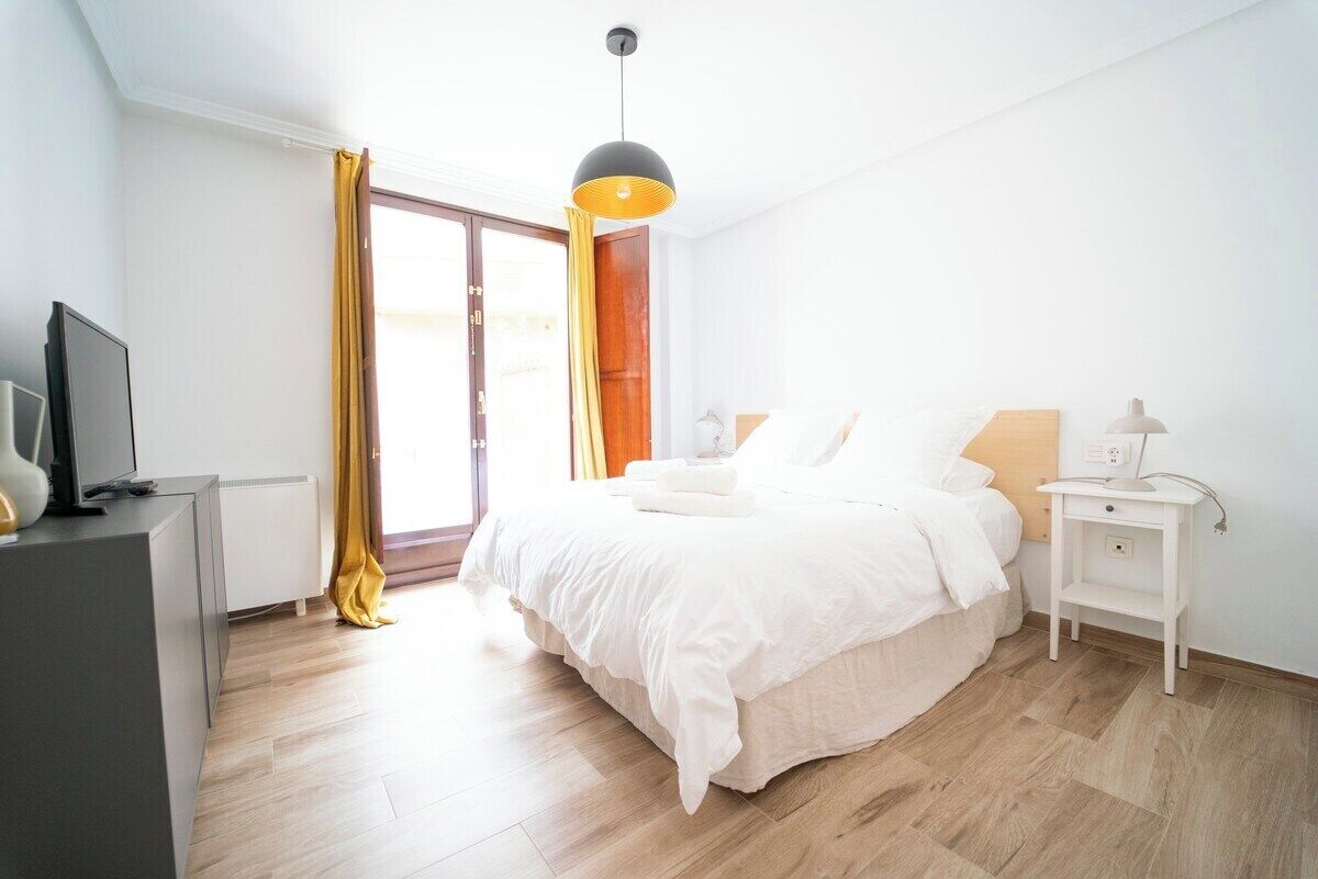 Ein modernes Schlafzimmer mit Bett, Nachttisch und Fernseher auf einer Kommode.