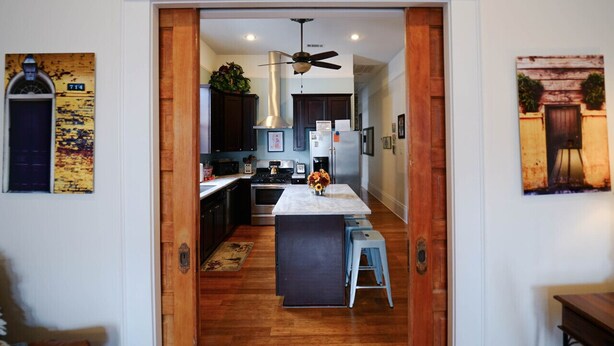 A modern kitchen with wooden flooring, a central island, and dark cabinetry. - Vintage Frenchmen Hideaway,6Blocks to Quarter+Jazz (New Orleans)
