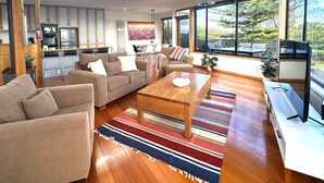 Un salón moderno con sofá, mesa de centro y ventanas amplias que ofrecen vistas al exterior.