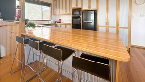Una cocina moderna con una isla de madera, taburetes de bar, un refrigerador y un microondas.