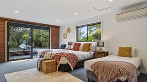 A modern bedroom with two beds, large windows, and a view of the outdoors. - Lumeah Retreat Bruny Island (Adventure Bay)