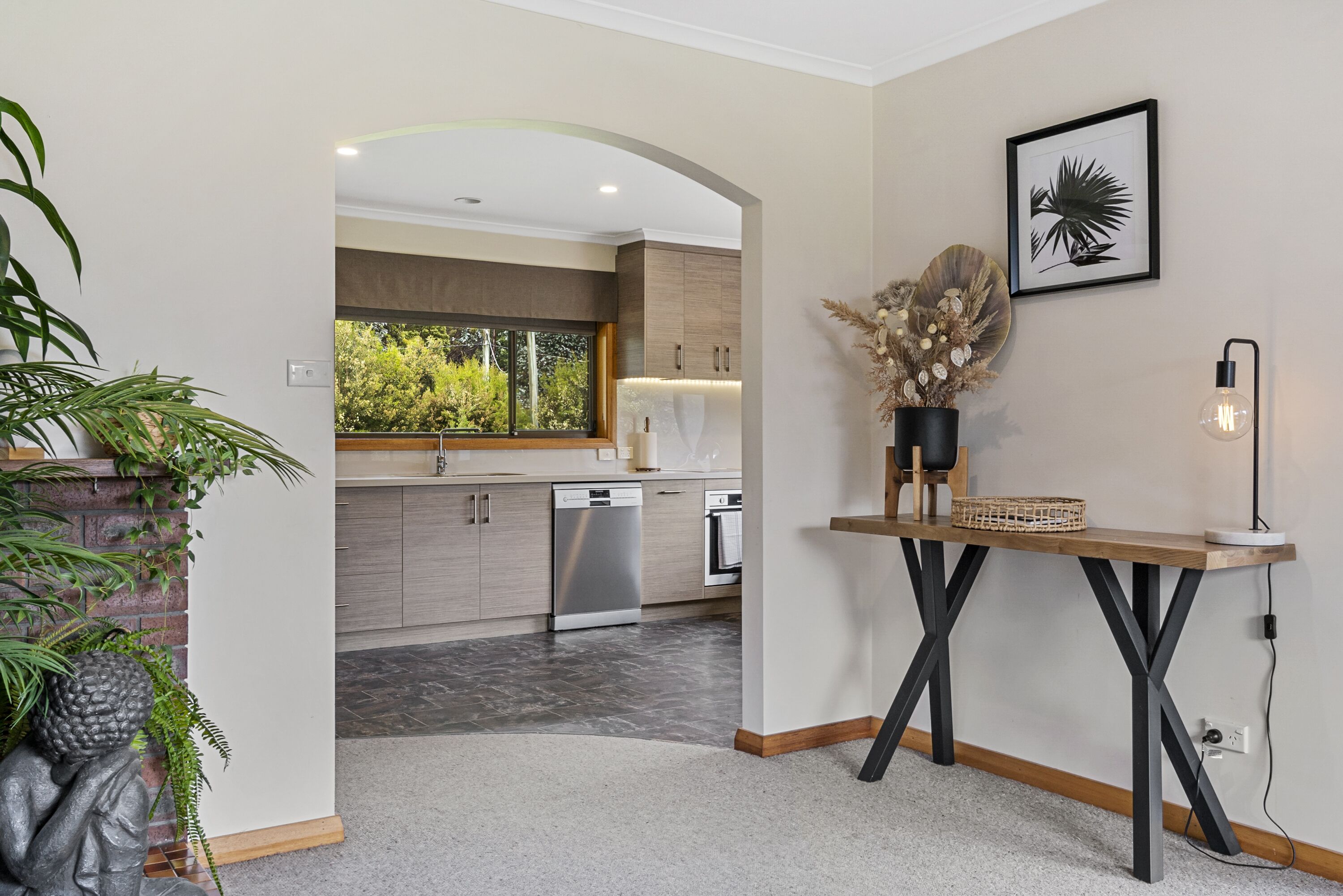 A modern kitchen with a view to the outdoors, a dining area with a table and chairs, and a decorative wall piece.