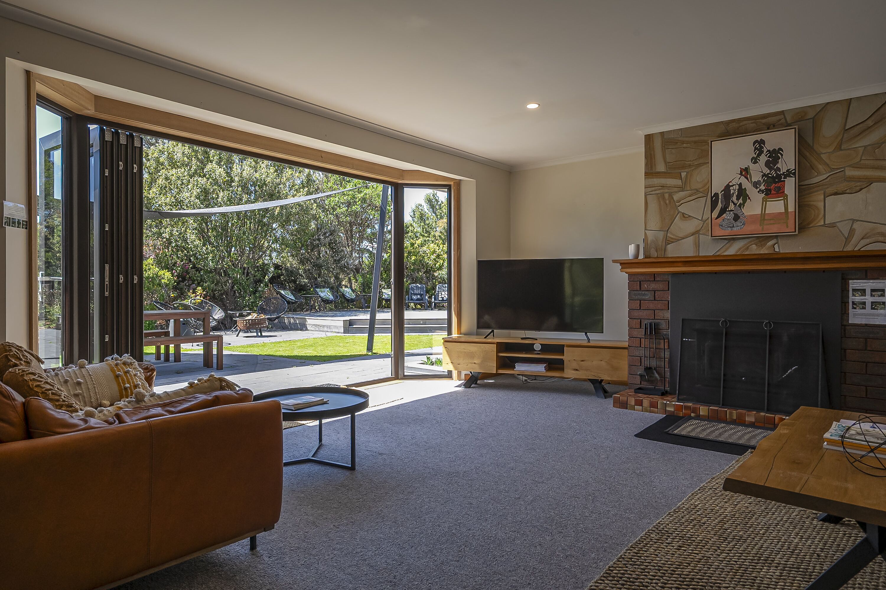 A modern living room with a large TV, fireplace, and sliding glass doors leading to an outdoor area.