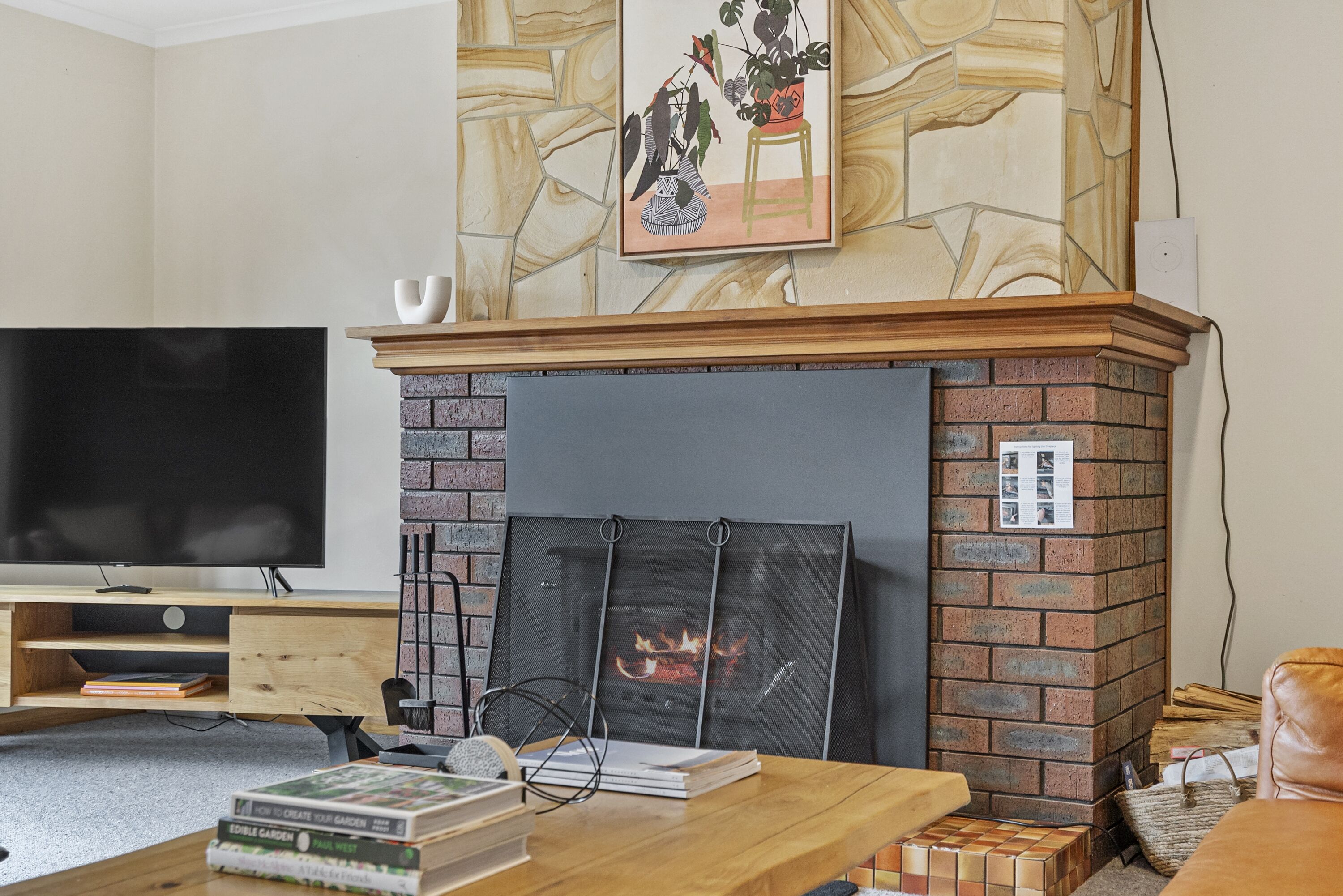 Una sala de estar con chimenea, televisor y estantería.