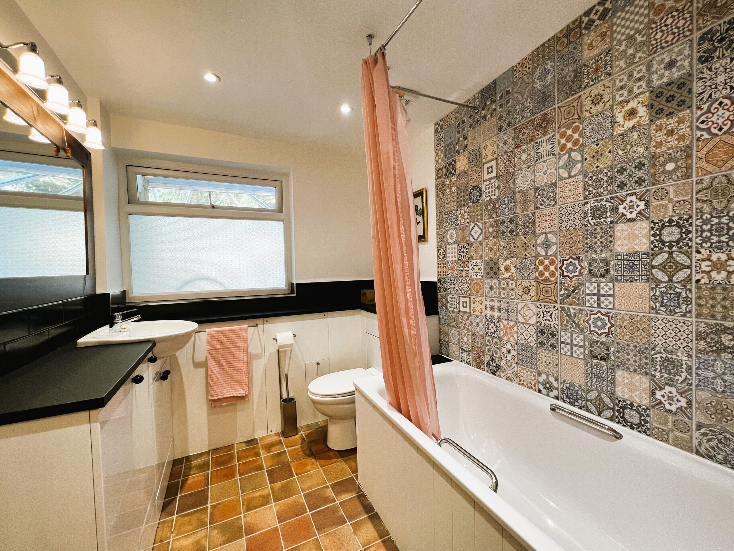A bathroom with a bathtub, toilet, sink, and a window.