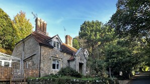 A stone house with a sloped roof, a chimney, and a small window.