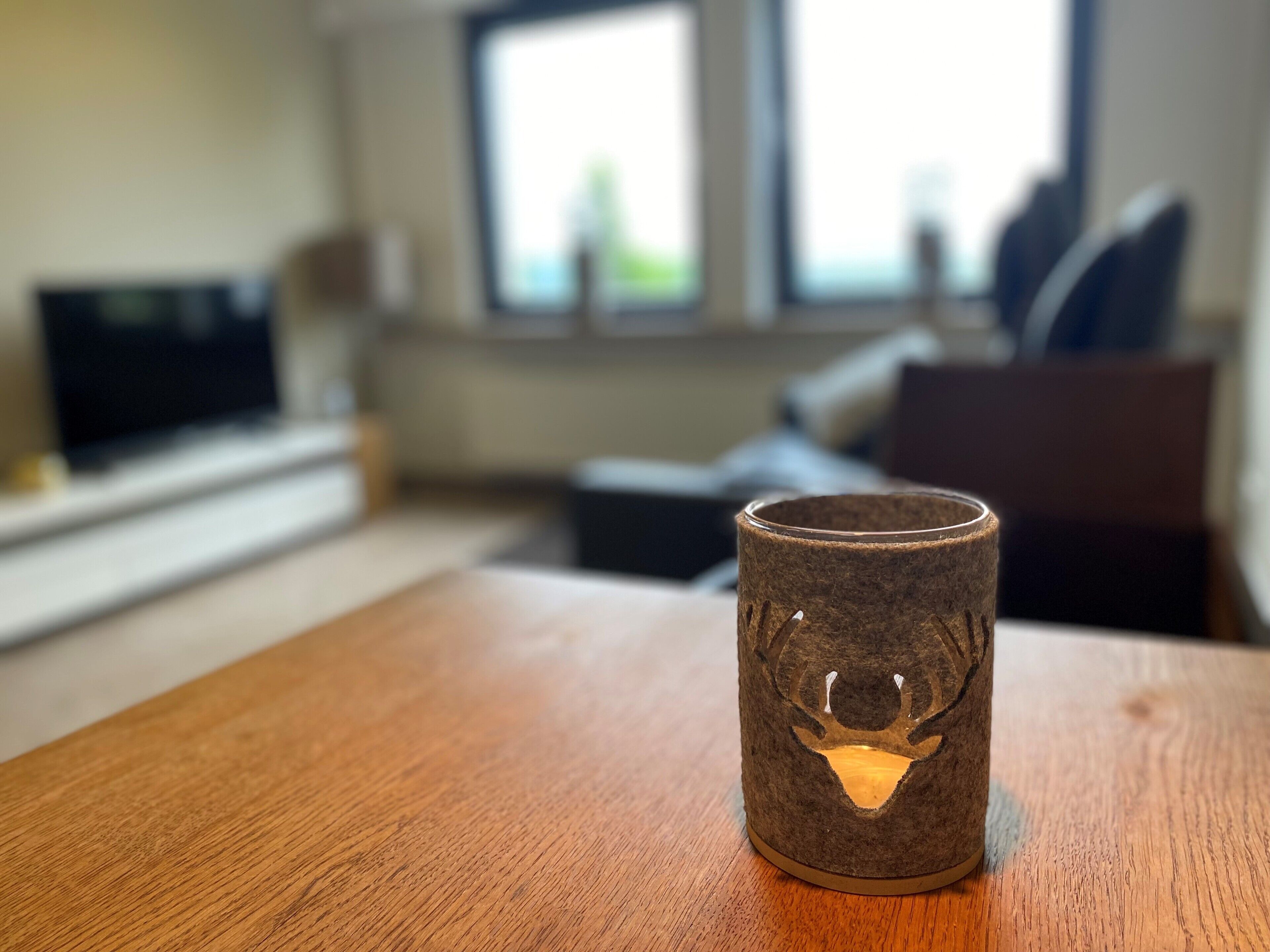 A wooden table with a felt mug featuring a deer design.