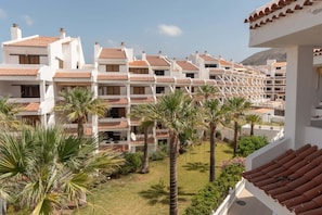 Un hotel con numerosi balconi, palme e montagne sullo sfondo.