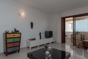 Un soggiorno moderno con televisione, un mobile colorato e un balcone con vista.