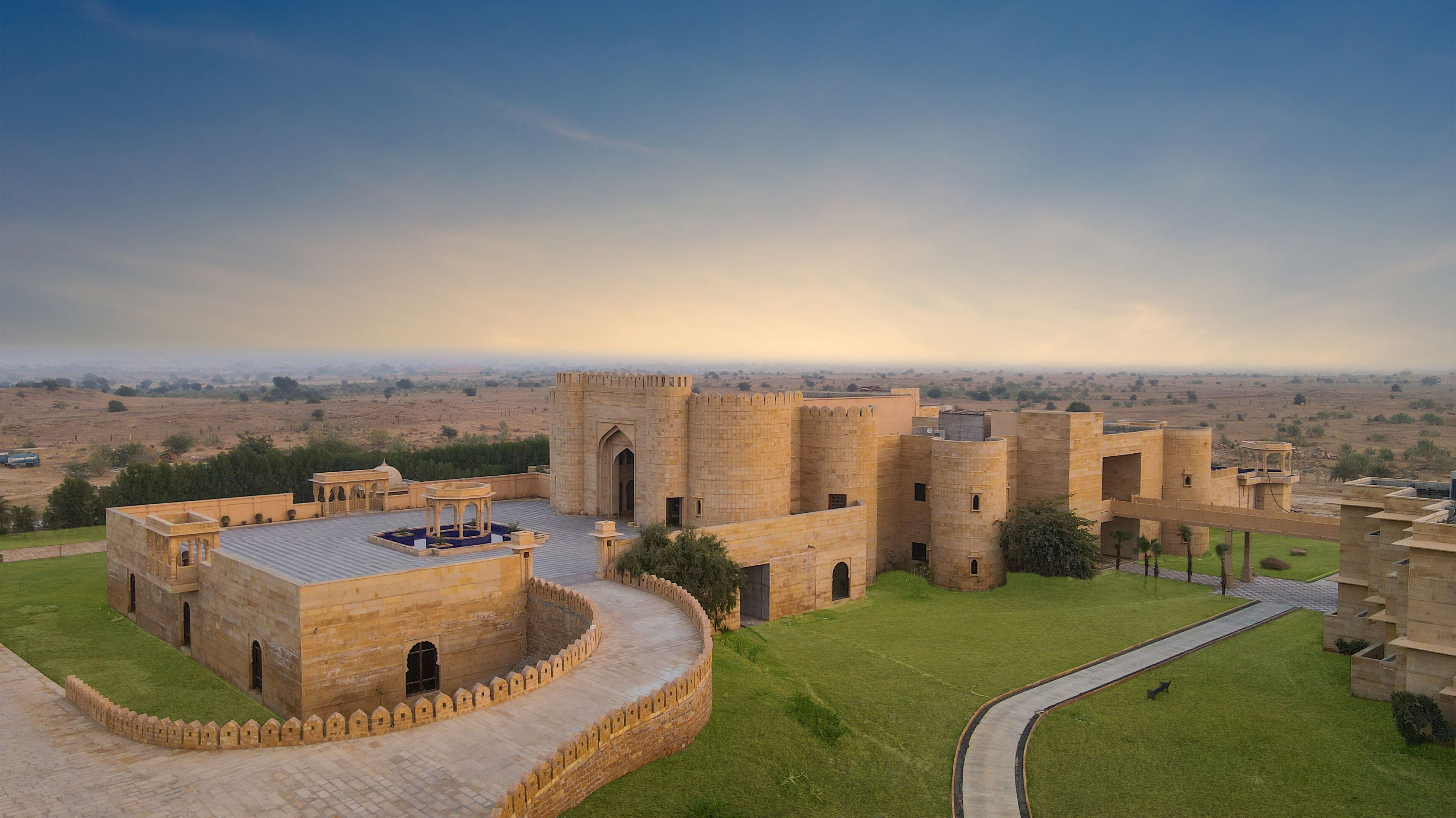 A historic fort with a central courtyard, surrounded by walls and towers, overlooking a flat landscape.
