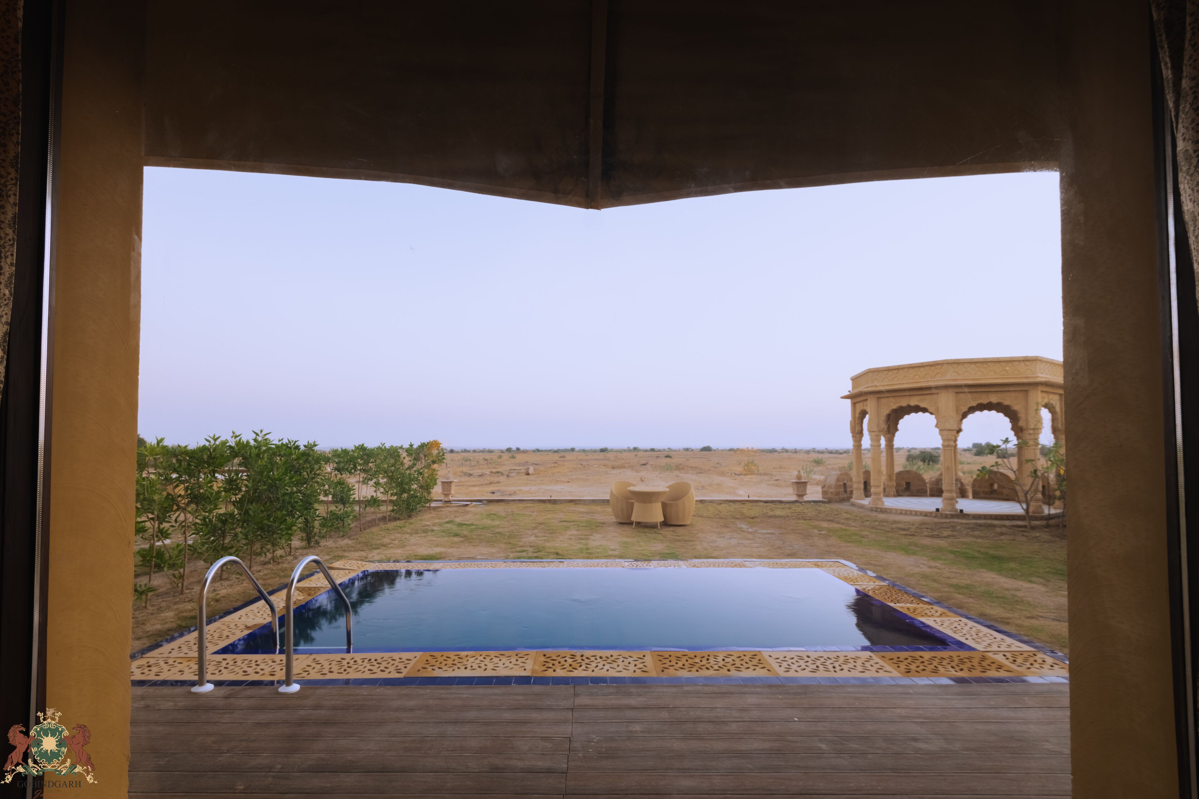 A pool with a view of a desert landscape and a traditional archway structure.