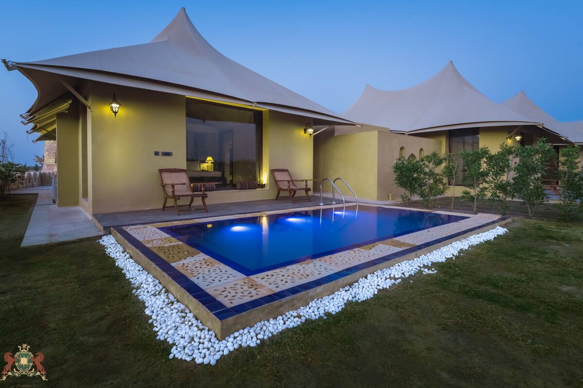 Una villa moderna con piscina, mobiliario exterior y un porche cubierto.