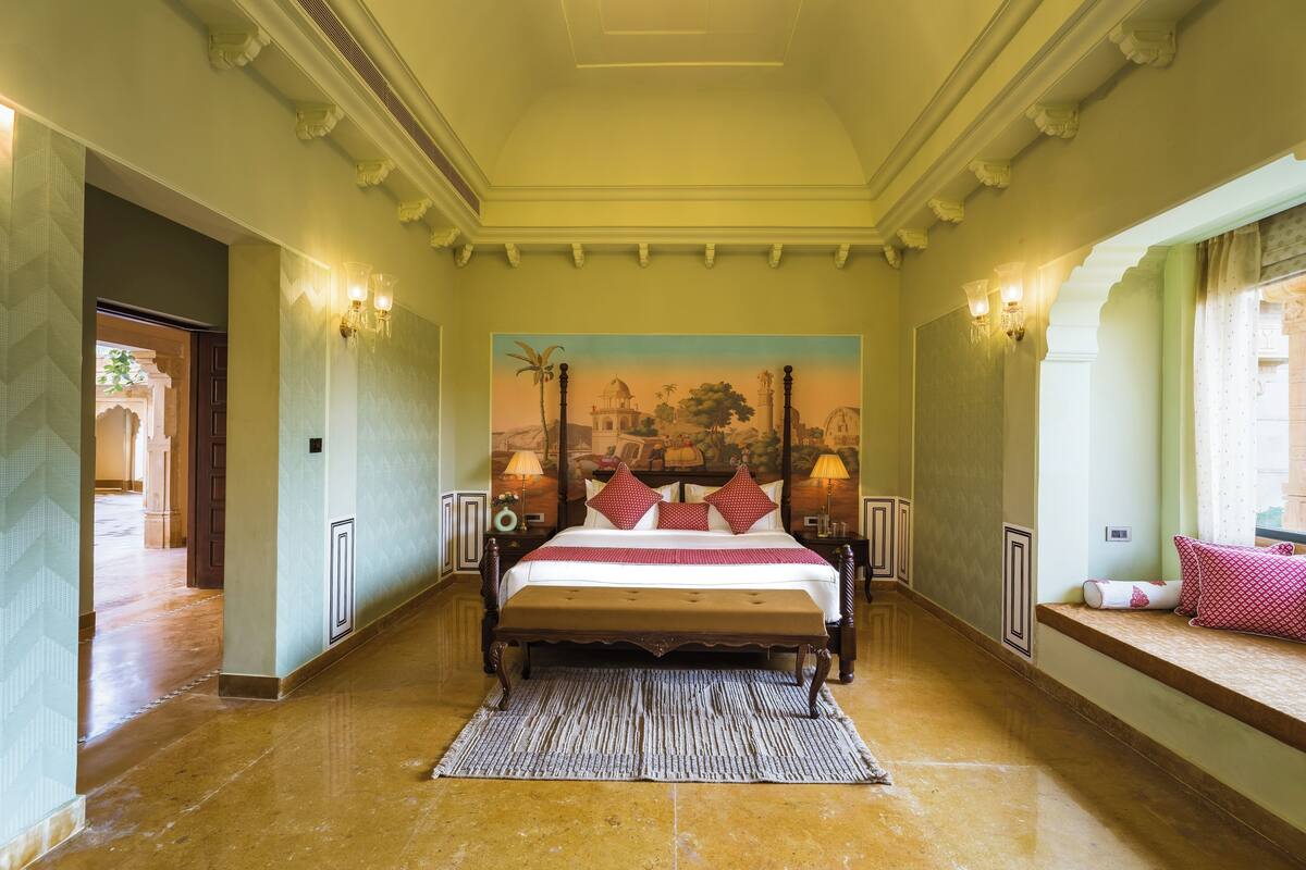 Un dormitorio amplio con una cama grande, un mural decorativo y vistas a un patio.