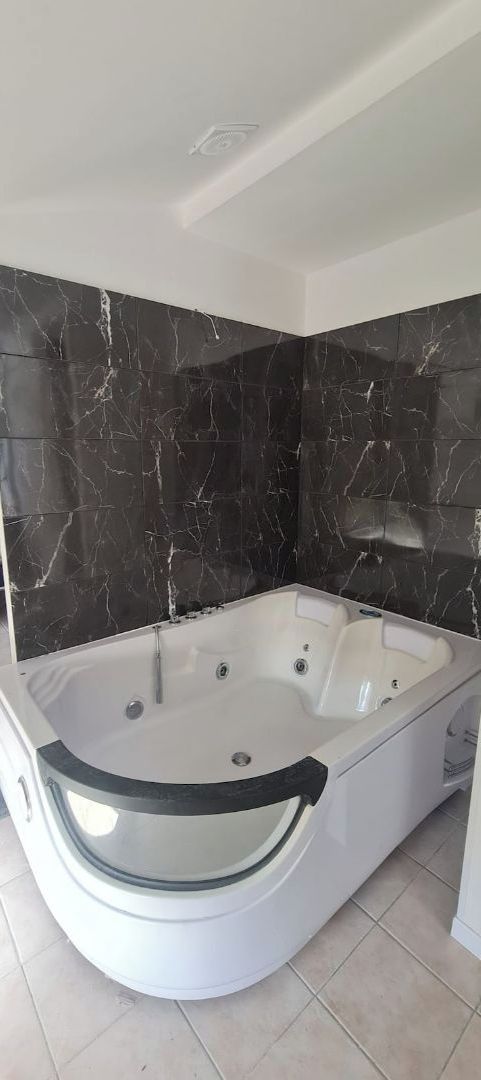 Une salle de bain moderne avec une baignoire sur pieds, des murs en marbre foncé et un sol carrelé.