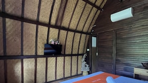 Une pièce comprenant un lit, une petite table, une étagère avec des objets décoratifs et un ventilateur de plafond.