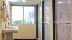 A bathroom with a sink, a window, and marble walls. - Hotel Golden suites Vashi Navi mumbai  (Navi Mumbai)