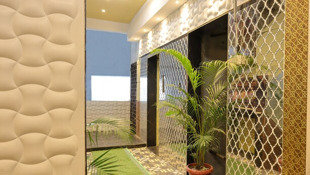 A corridor with patterned walls, a green mat, and potted plants. - Hotel Golden suites Vashi Navi mumbai  (Navi Mumbai)