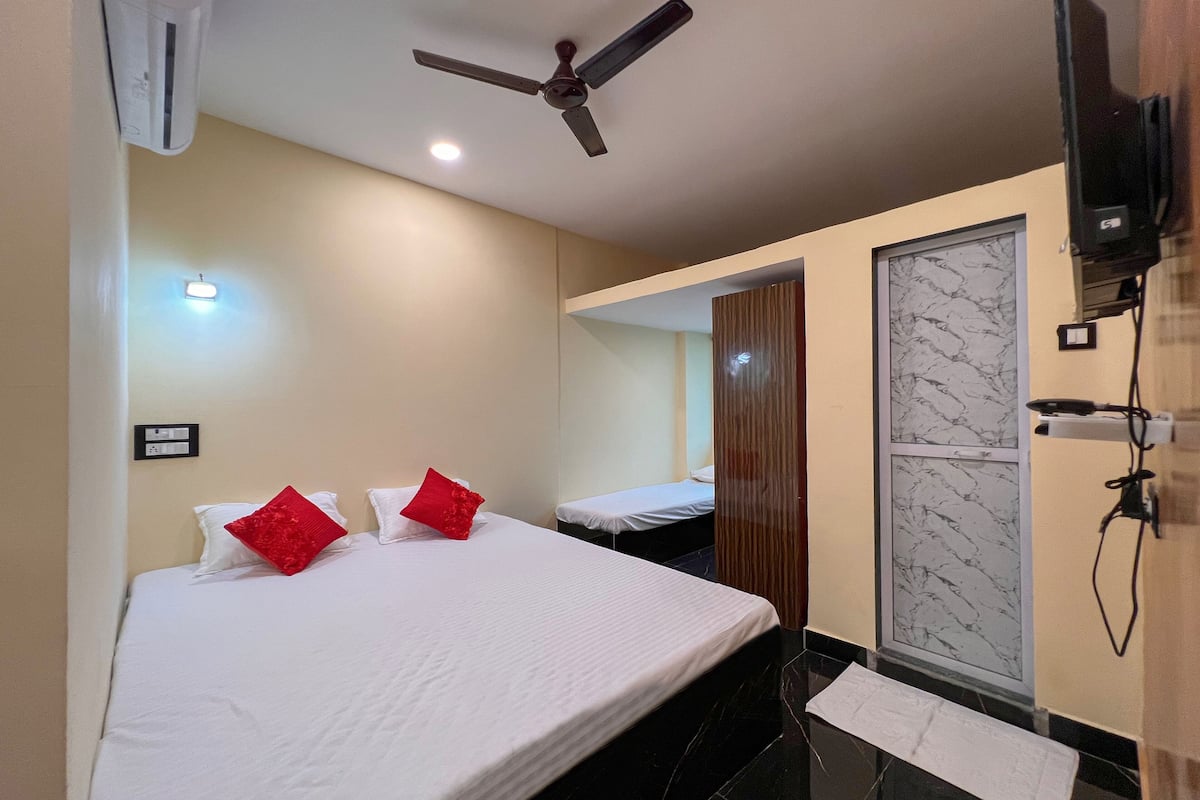 A hotel room with a bed, a ceiling fan, a mirror, and a television mounted on the wall.