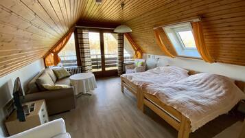 Ein gemütliches Schlafzimmer im Dachgeschoss mit Holzbalkendecke, einem Bett, einer Couch und einem kleinen Tisch.