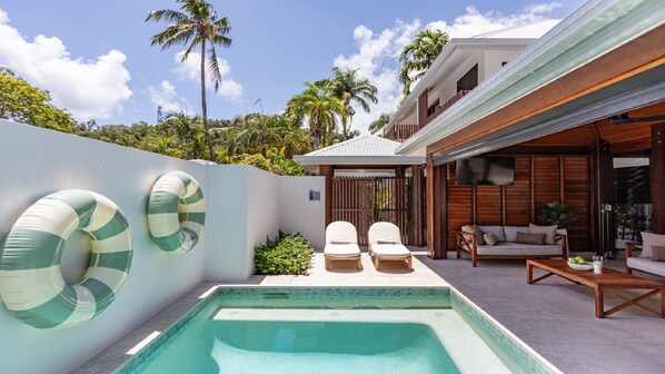 Relax by the pool surrounded by lush greenery and palm trees.