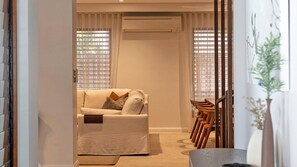 Relax in this inviting living space with a comfortable sofa, wooden chair, and large window offering a view.