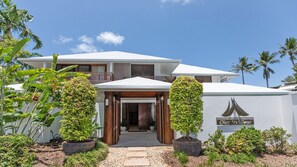 Welcome to Chez Willow, a charming two-story building surrounded by lush greenery and a beautiful pergola entrance.