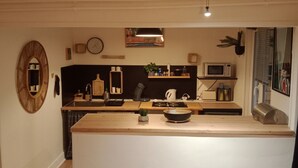Une cuisine moderne dotée d’un plan de travail en bois, d’un four à micro-ondes, d’une bouilloire et d’un évier.