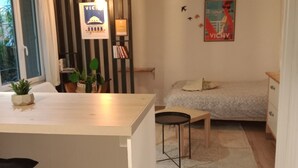 Un espace de vie moderne et compact comprenant un coin cuisine, un espace repas et une chambre.