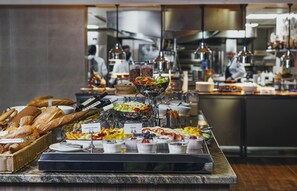 Un buffet con diversi cibi, tra cui pane, frutta e yogurt.