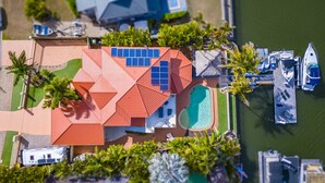 An aerial view of a resort with a swimming pool, multiple boats, and solar panels. - Paradise on Banksia Canal (BANKSIA BEACH)