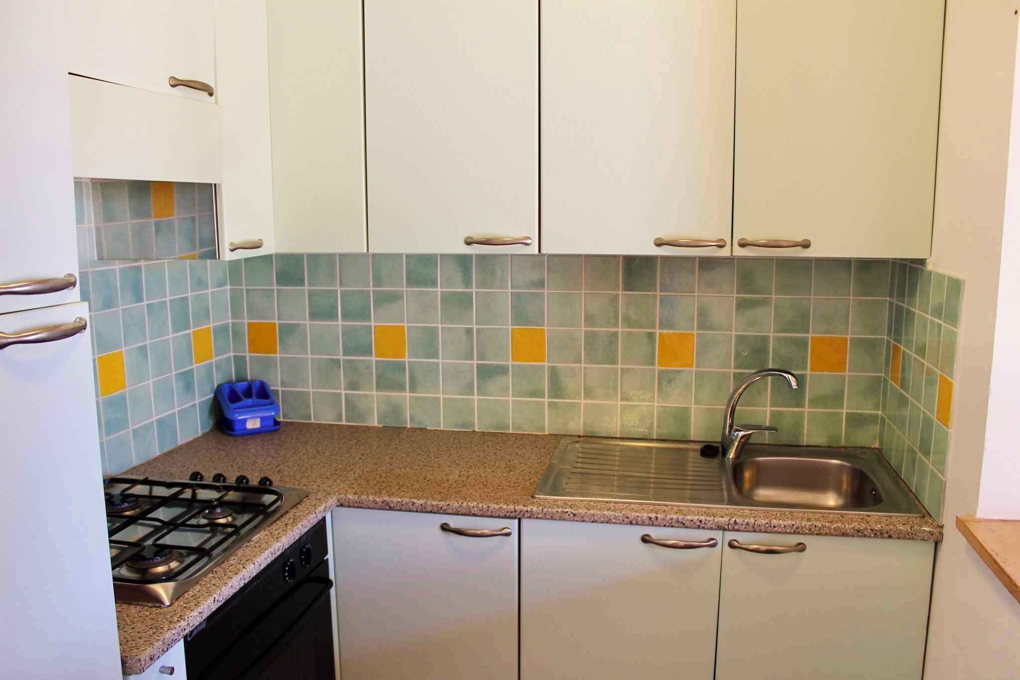 A kitchen with white cabinets, a gas stove, a sink, and a tiled backsplash.