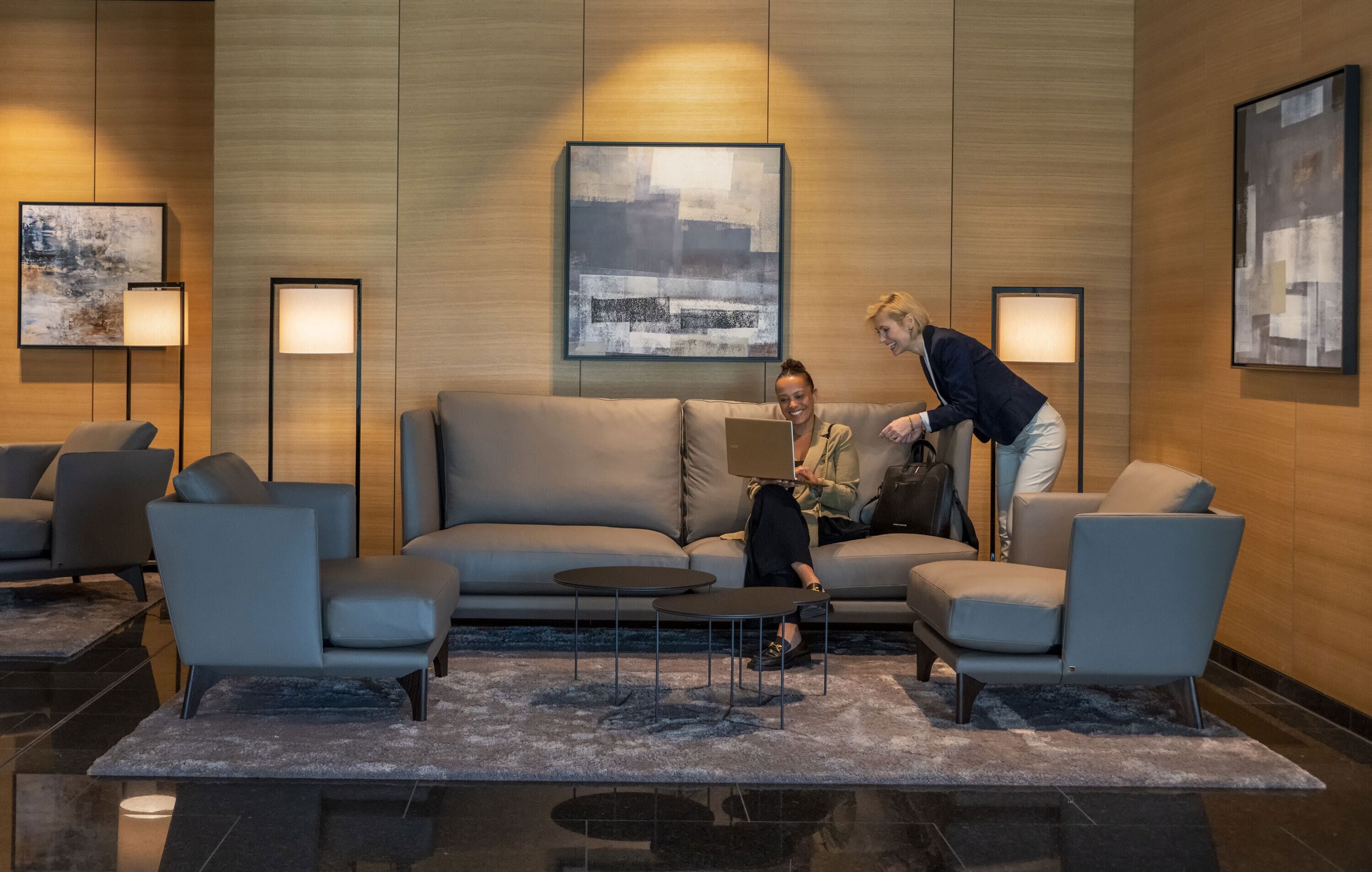 A modern lobby with a sofa, two armchairs, a coffee table, and floor lamps.