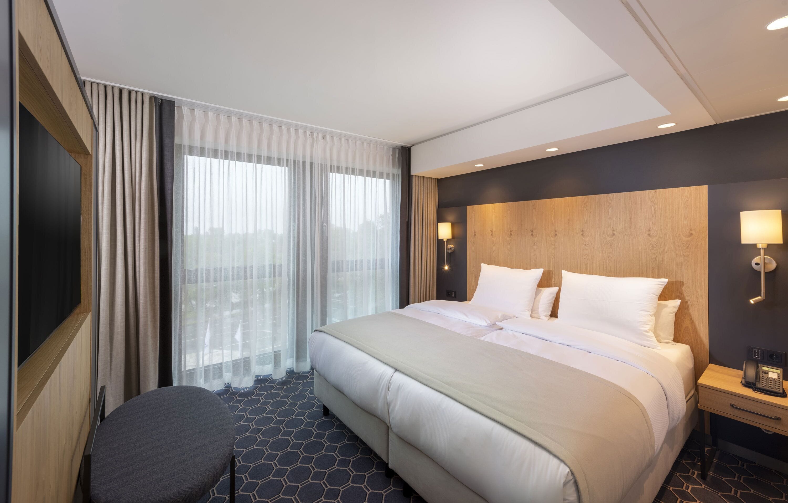Une chambre d’hôtel moderne, dotée d’un grand lit, d’un bureau et d’une chaise.