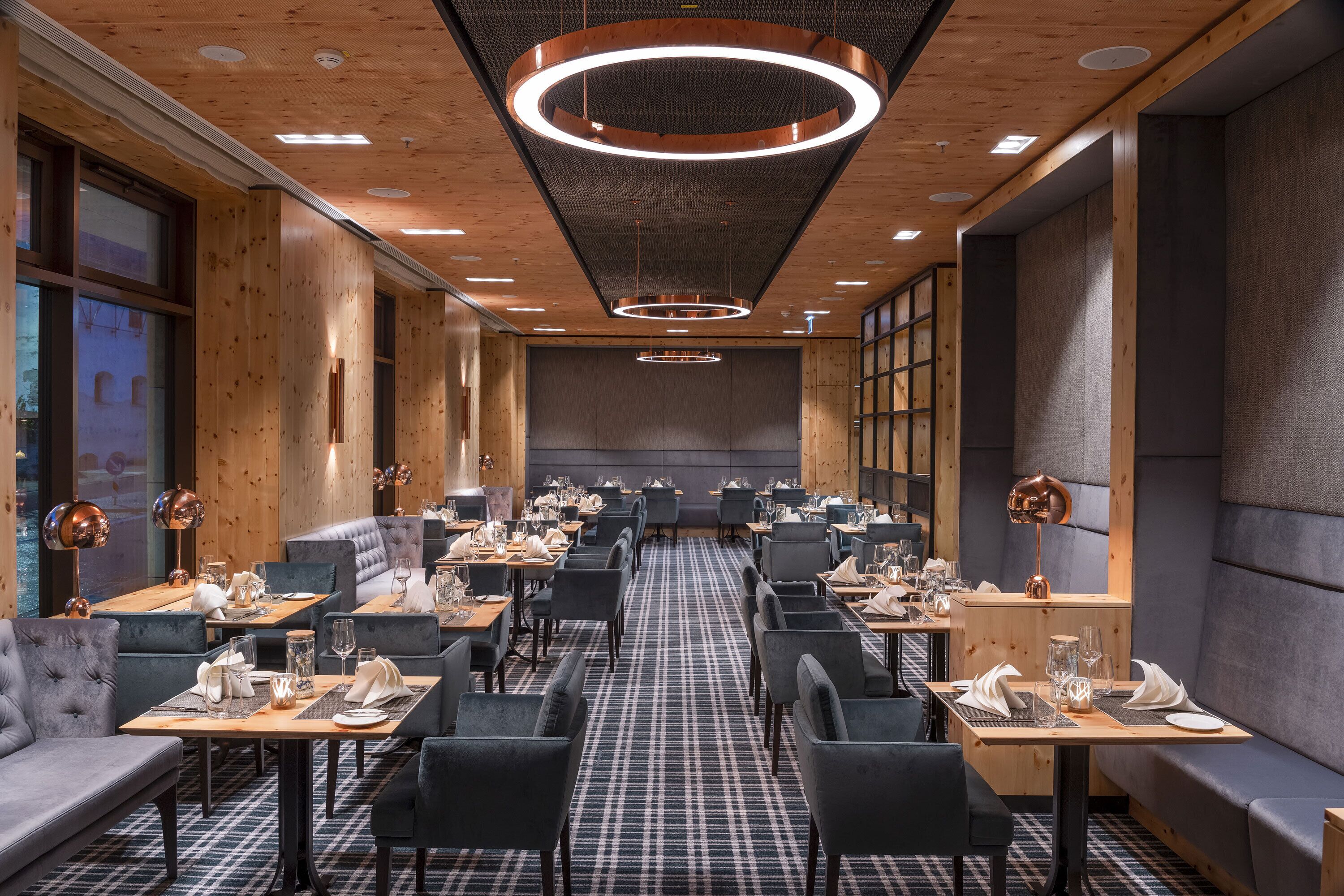 Een modern restaurant met houten details, zwart-wit geruit vloer en een centraal zitgedeelte met een lange tafel.