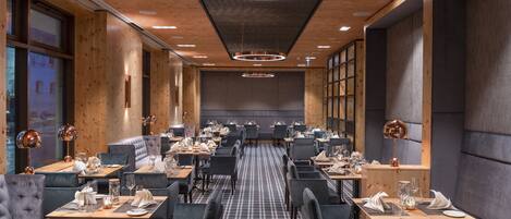 Een modern restaurant met houten details, zwart-wit geruit vloer en een centraal zitgedeelte met een lange tafel.