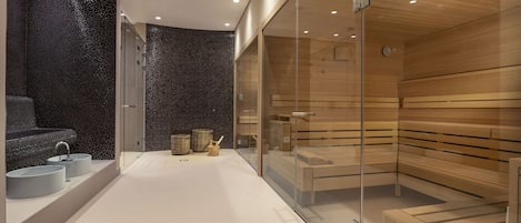 A modern spa with a glass-enclosed sauna, a separate shower area, and a seating area with a wooden bench.