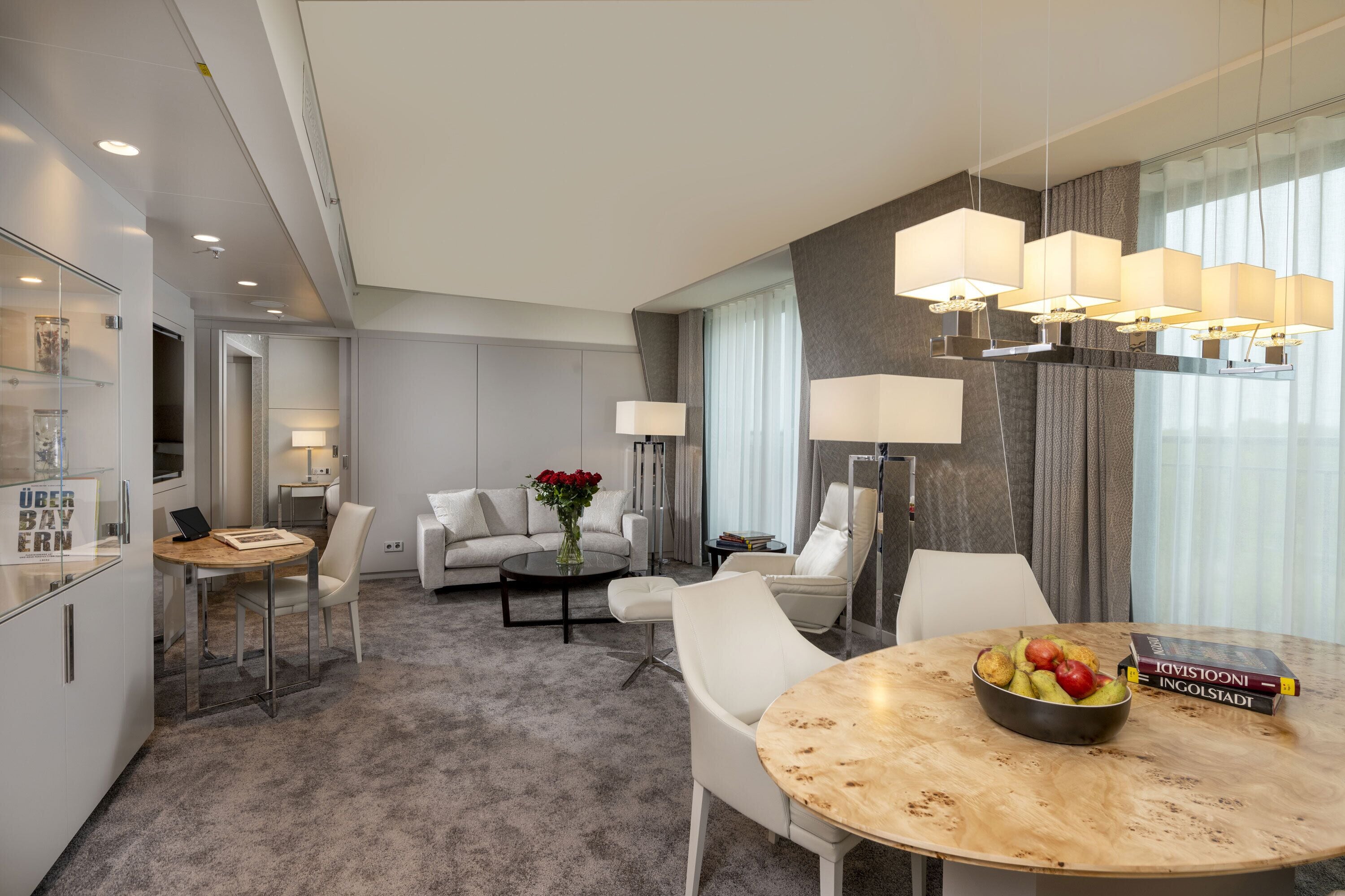 Una habitación de hotel moderna con comedor, sofá, mesa de centro y lámpara.