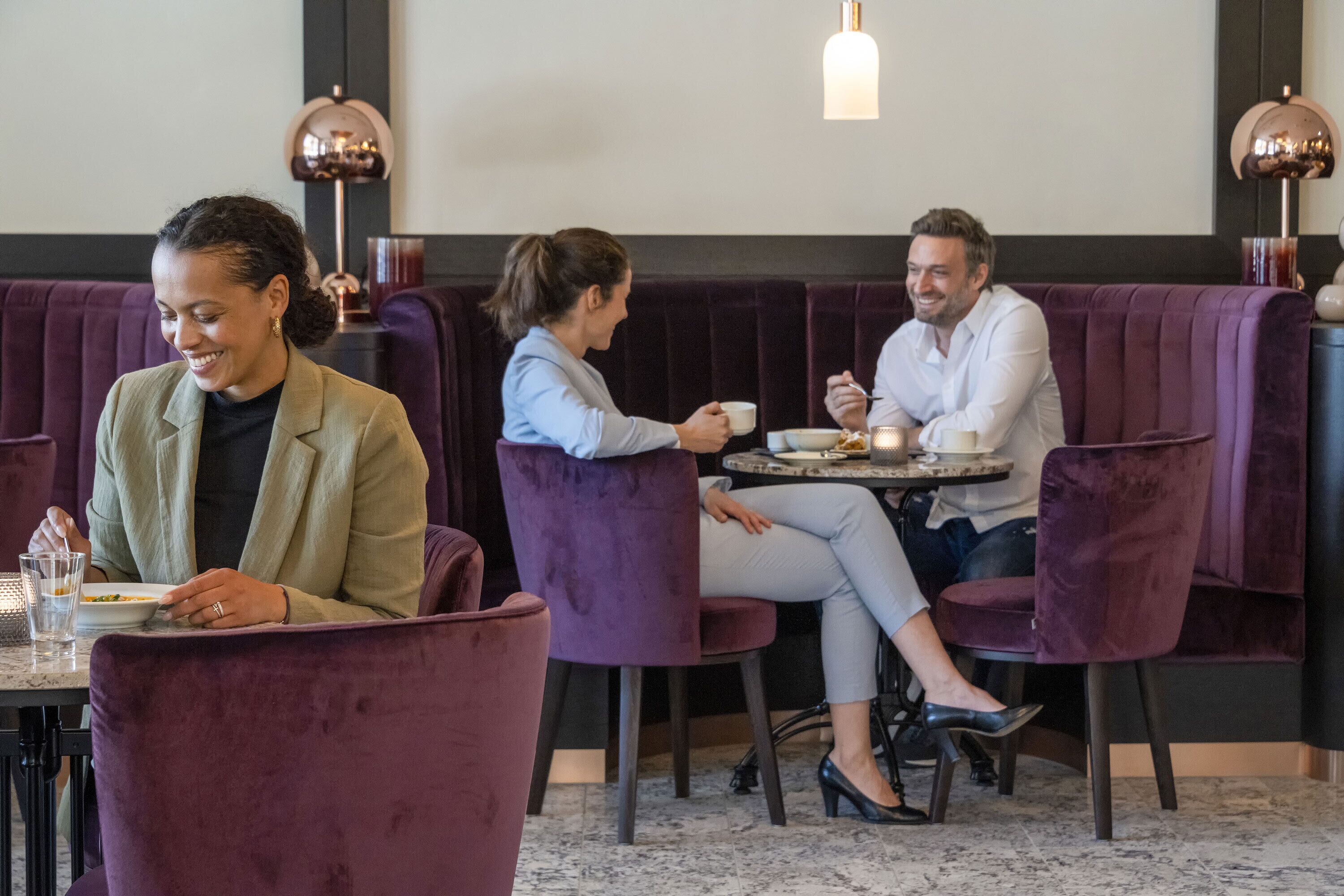 A restaurant with purple velvet booths and a marble floor.