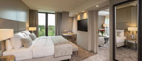 Habitación de hotel moderna con una cama grande, televisión, escritorio y balcón con vistas.