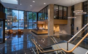 Een moderne lobby met een receptiebalie, een zithoek en een trap.