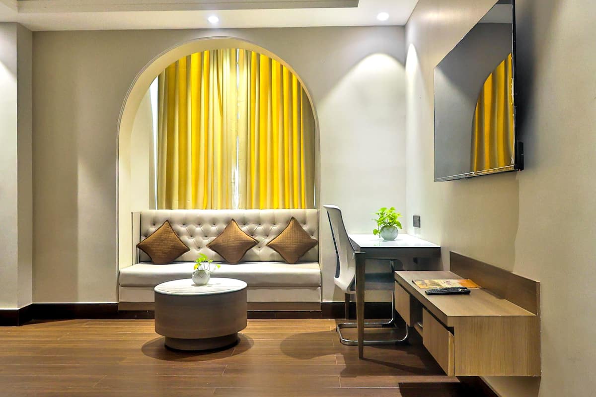 A modern living room with a sofa, a round coffee table, a desk with a chair, and a large mirror on the wall.