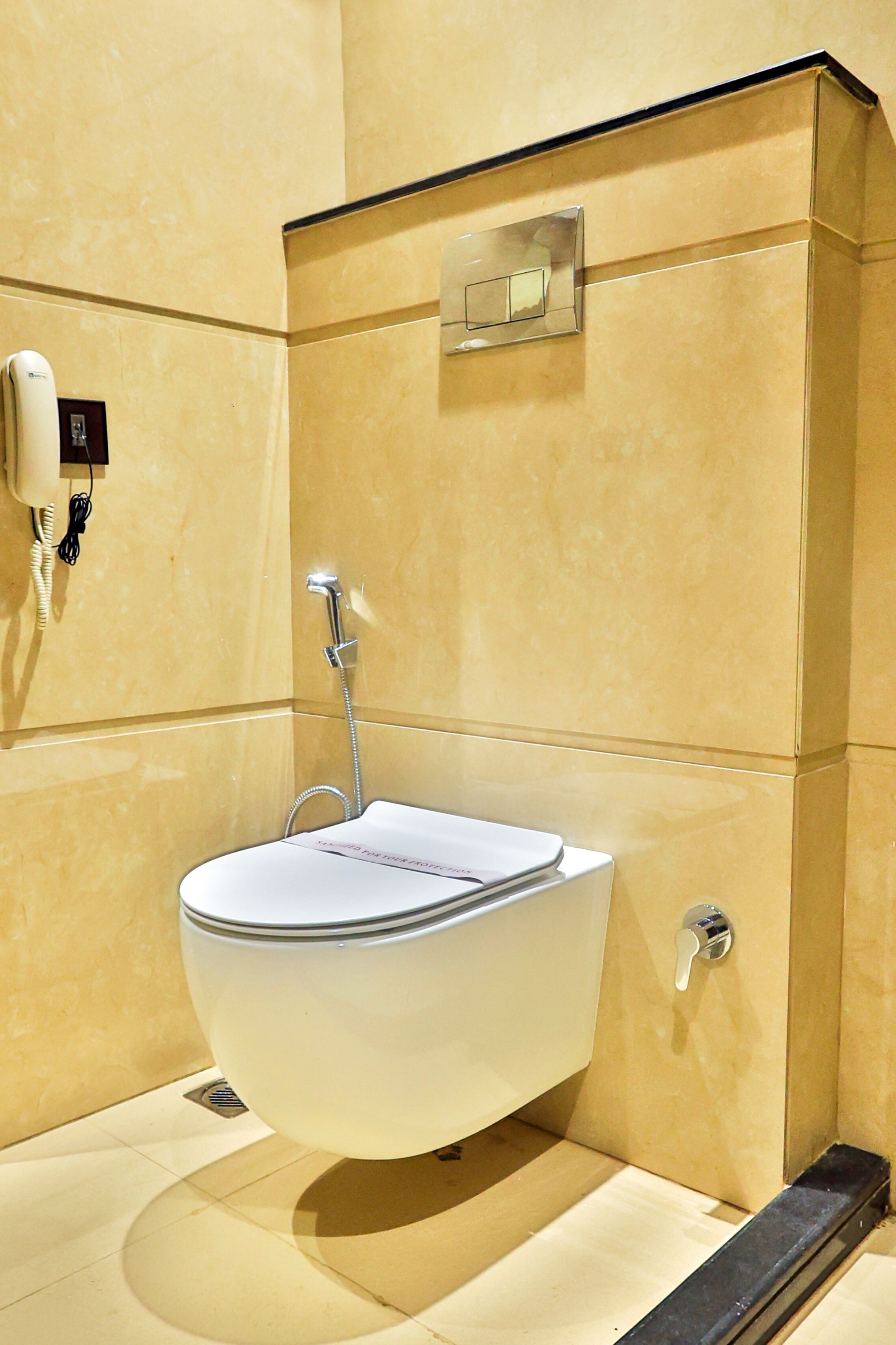 A modern bathroom with a wall-mounted sink, a hand dryer, and a flush toilet.