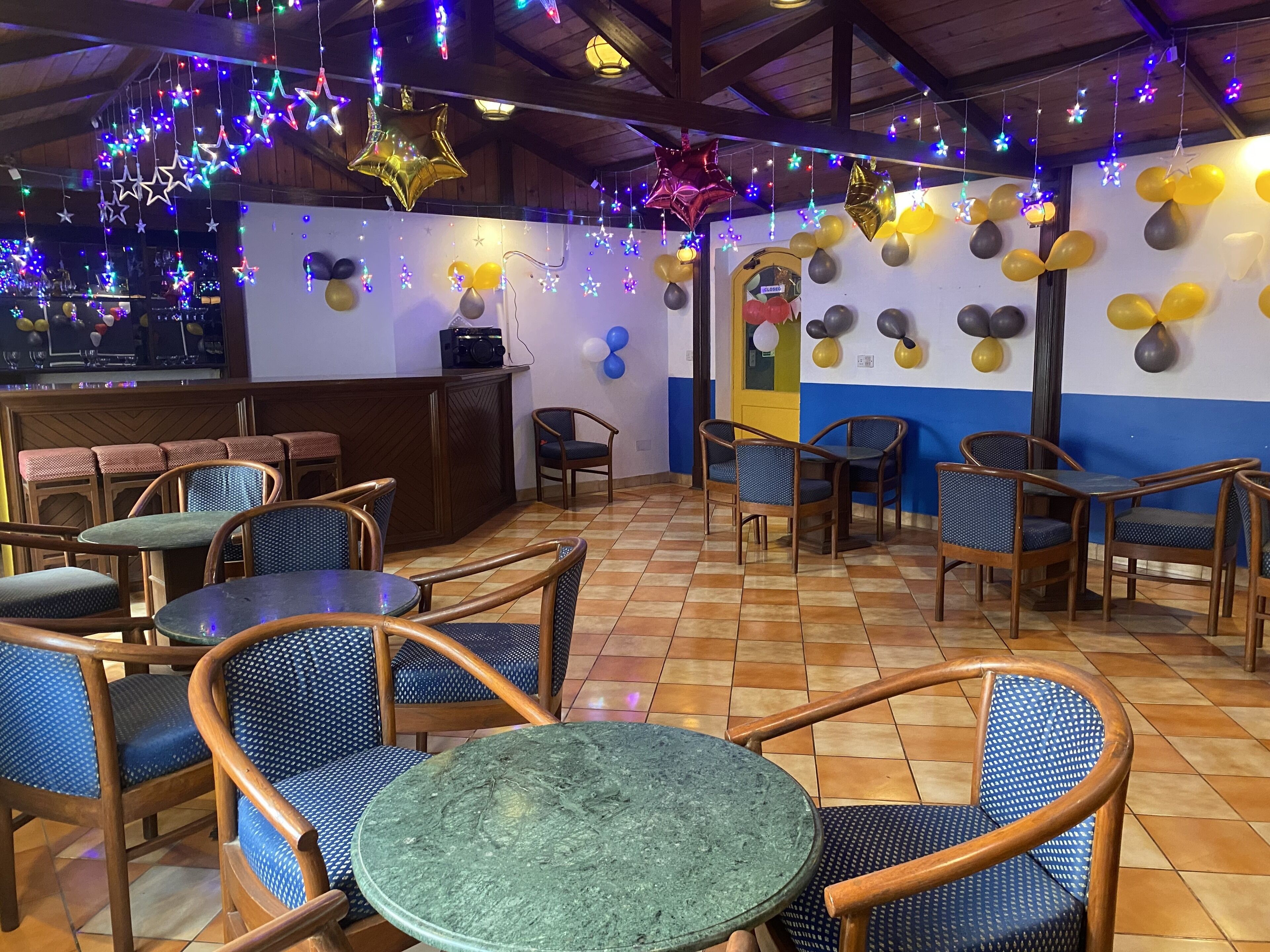 A restaurant with wooden furniture, a tiled floor, and star-shaped balloons.