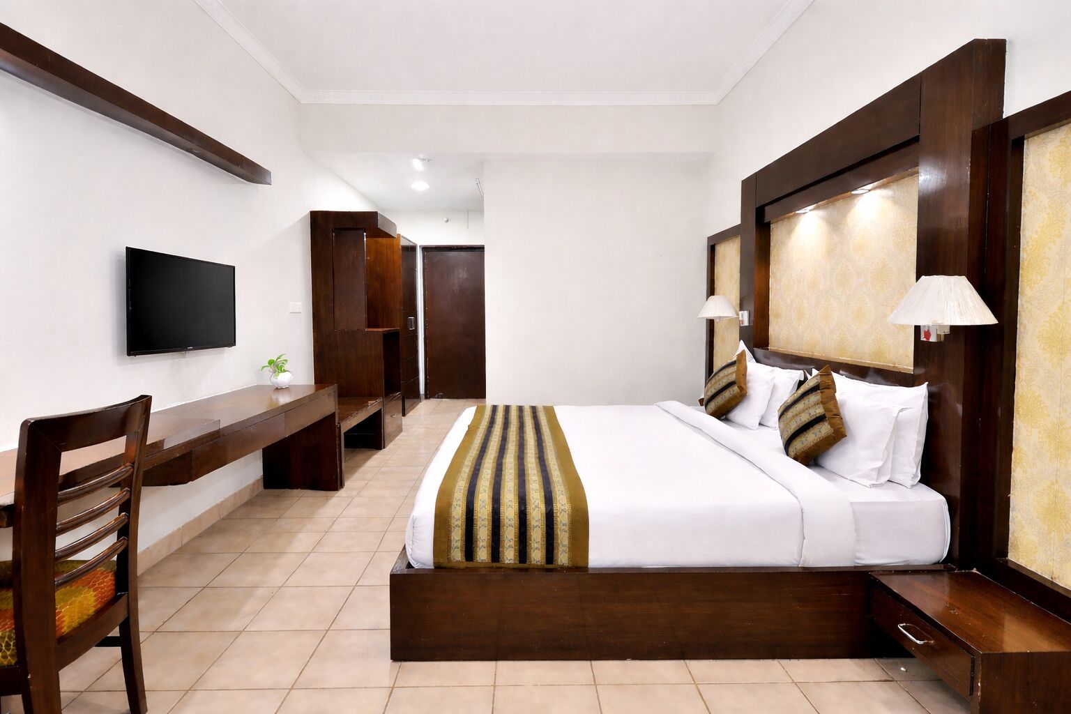 Een hotelkamer met een bed, nachtkastjes, een bureau, een stoel, een televisie en een kledingkast.