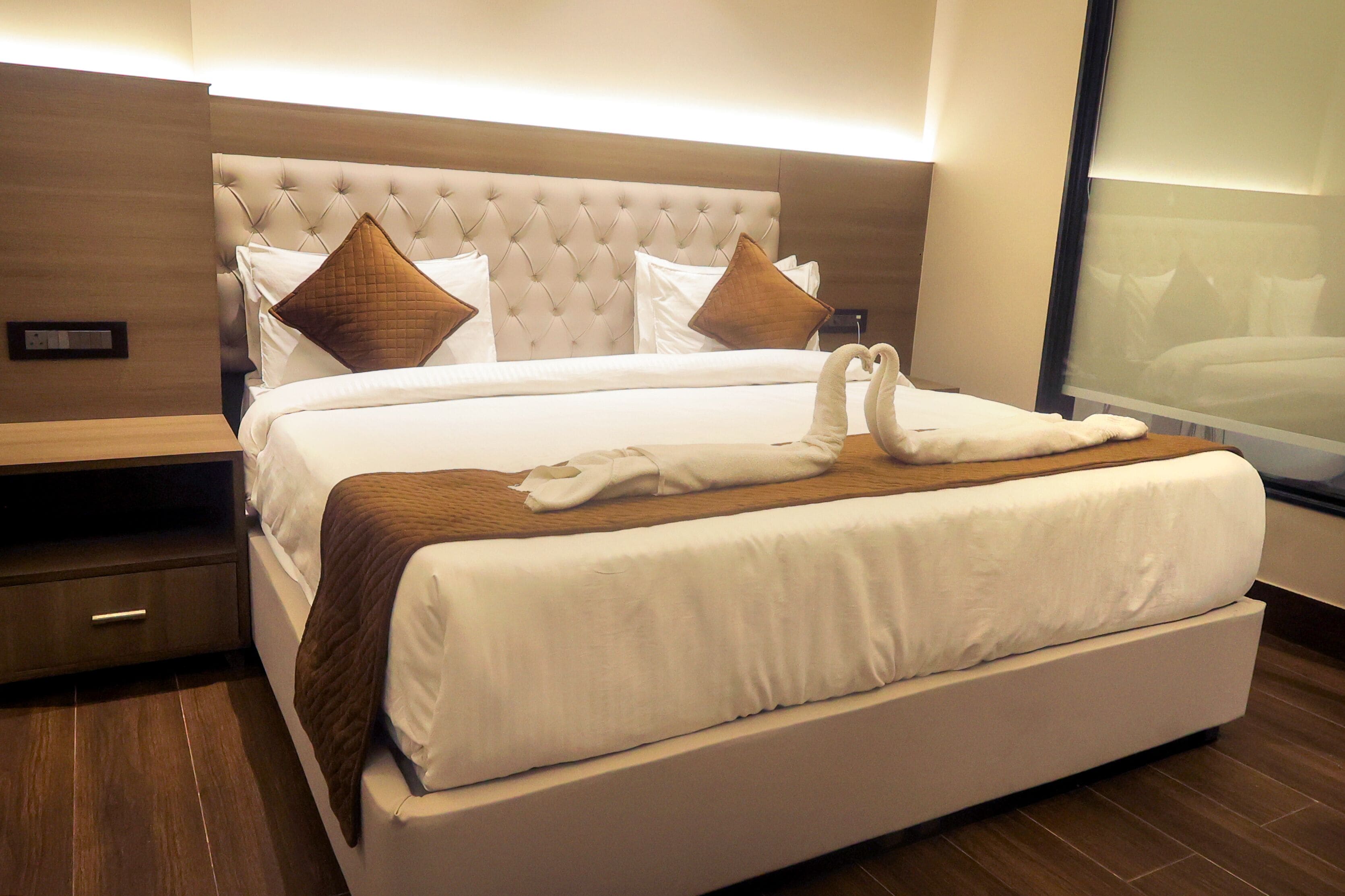 Ein Hotelzimmer mit einem großen Bett, einem Holzkopfstück und einem Nachttisch mit Schublade.
